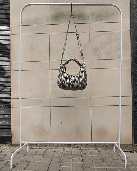 Bolso acolchado plateado con asa y bandolera, vista frontal colgado